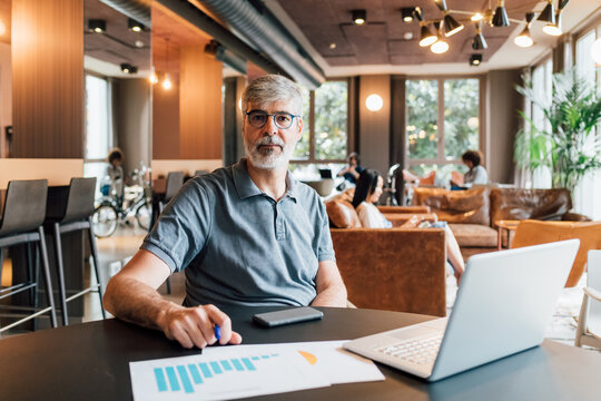 Italy, Portrait of businessman sitting at table in creative studio