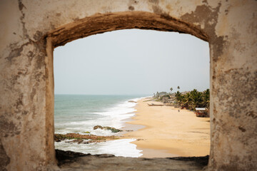 Ghana, Cape Coast, Beach and sea seen through stone arch