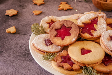 Delicious homemade Christmas cookies with jam, copy space. Traditional Linzer cookies on a dark table, copy space