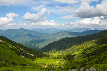 Fototapeta na wymiar Green fields and mountains, blue sky with clouds. Carpathian mountains in late summer. Carpathians, Ukraine