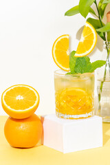 glass with chilled orange drink, two orange slices falling into the glass, refreshing summer cocktail