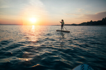 Woman practicing SUP, board balancing on paddle board