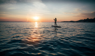 Girl on stand up paddle board enjoy sunset sea