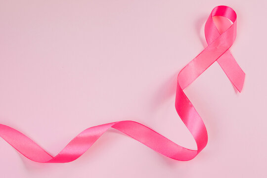 Pink ribbon on colored background. Breast Cancer Awareness Month symbol. Women's health care concept. Promotion of campaign to fight cancer.