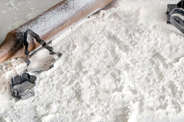 Festive culinary background flour, rolling pin and Christmas baking mould. Concept home baking. Baking class or recipe concept on light background, sprinkle wheat flour with free copying space.