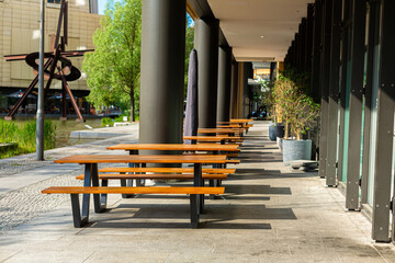 Deserted benches on the summer terrace of the restaurant - obrazy, fototapety, plakaty