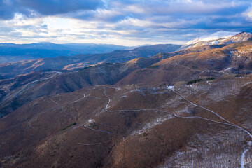 Kopaonik mountain range in Serbia. Aerial view on Kopaonik National Park. Sunset under mountains, hills and meadows. Winding road along the mountains