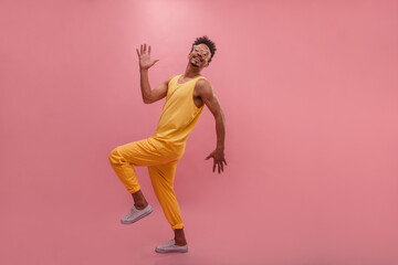 Fashionable young African man dancing vigorously in place with copy space. Quirky sunglasses and...