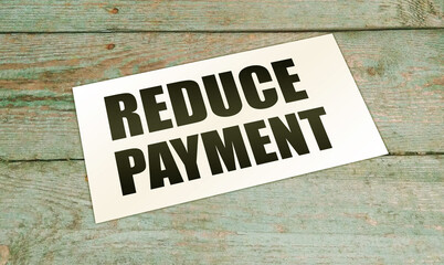 Reduce payment text on card on wooden background. business concept