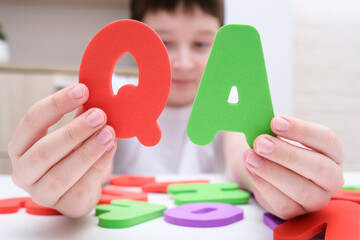 A boy holding colorful letters Q and A, questions and answers concept, solvation kids problems