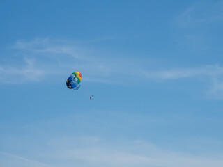 Parasailing with multi colored parachute against blue summer sky. Bulgaria. Copy space.