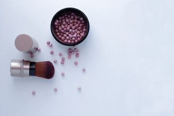 Blush balls of pink and cream color and a brush for applying blush on a white background with a place for text. top view, flat lay, copy space, isolate