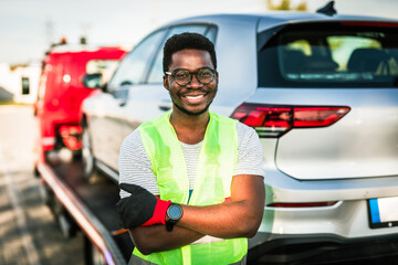Handsome young African American man working in towing service on the road. Roadside assistance...
