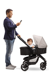 Full length profile shot of a father with a baby in a stroller standing and looking at a mobile phone