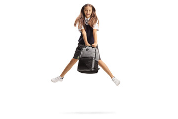 Happy schoolgirl with long hair jumping and holding a backpack