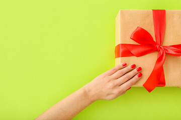 Female hand with beautiful manicure and gift box on color background