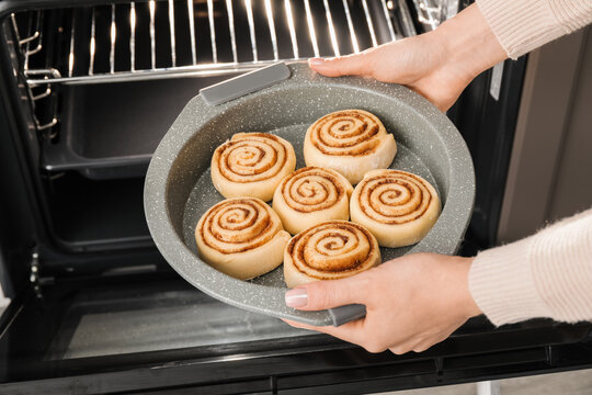 Woman putting uncooked cinnamon rolls in microwave oven