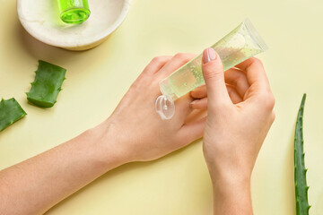 Woman applying aloe gel onto her hands on color background