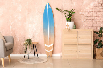 Interior of modern stylish room with surfboard and chest of drawers
