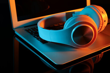 Modern laptop and headphones on color background, closeup