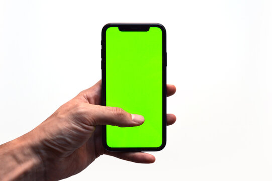 Photo of a hand holding a mobile device - iPhone template with green screen to add a customized image or text with chroma key - Smartphone blank screen to show an app, game or website on display