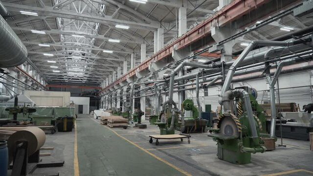 Interior of workshop for woodworking and making wooden molds, automatic machines, girder cranes and stacks with wood.