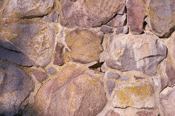 An old wall of granite stones of different sizes as a background.