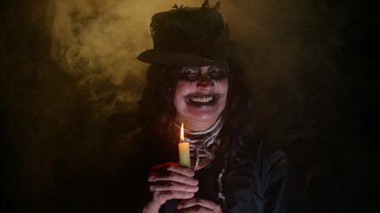 Creepy mature woman grandmother with Halloween stylish witch makeup. Old scary granny making voodoo...