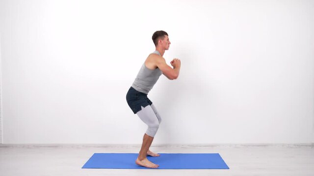 athletic man doing squats and jumping on fitness mat, squatting