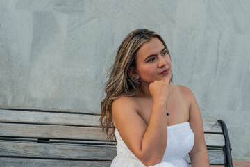 Naklejka premium Hispanic Woman sitting on a park bench and looking to the side
