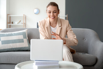 Young woman with laptop video chatting at home