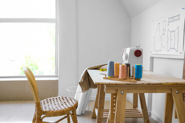 Tailor's workplace with sewing machine and threads in atelier