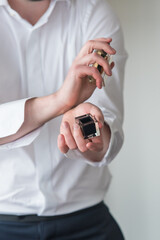 Vertical shot of a young man in a dress shirt putting on cologne and preparing for a wedding
