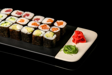 Plate with set of delicious maki rolls on dark background