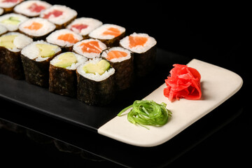 Plate with set of delicious maki rolls on dark background, closeup