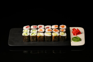 Plate with set of maki rolls on dark background