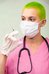 Health care worker in pink scrubs prepares a syringe for vaccination.