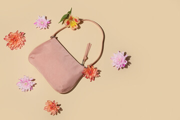 Stylish handbag and beautiful flowers on color background