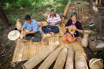 Asian elderly man and woman gathered together to weave from bamboo by hand. Handicrafts of local...