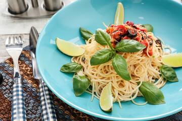 Plate of tasty Pasta Puttanesca on table, closeup