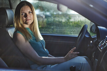 Fototapeta na wymiar Young european woman with blond hair is driving car.