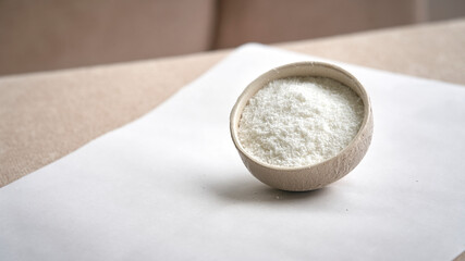 view of grated coconut in ceramic bowl on white background.