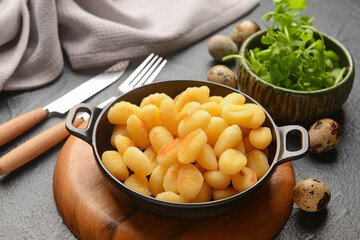 Frying pan with tasty gnocchi on dark background
