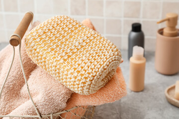 Fototapeta na wymiar Basket with soft bath towels and loofah sponge in bathroom