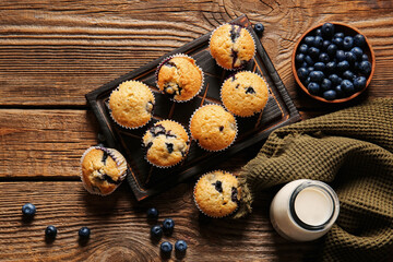 Composition with tasty blueberry muffins, berries and milk on wooden background