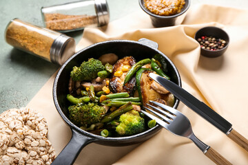 Frying pan with different vegetables, spices and rice crackers on color background, closeup