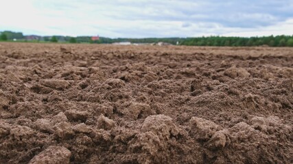 Plowed Brown Soil Field with Green Hills in Background