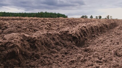 Plowed Brown Soil Field with Green Hills in Background