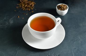 Cup of tasty hojicha green tea on black background