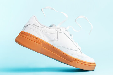 Levitation of white sneaker close-up on blue background.